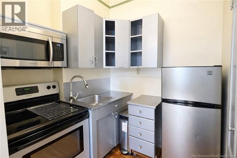 A kitchen with a stainless steel refrigerator, microwave, oven, and sink.