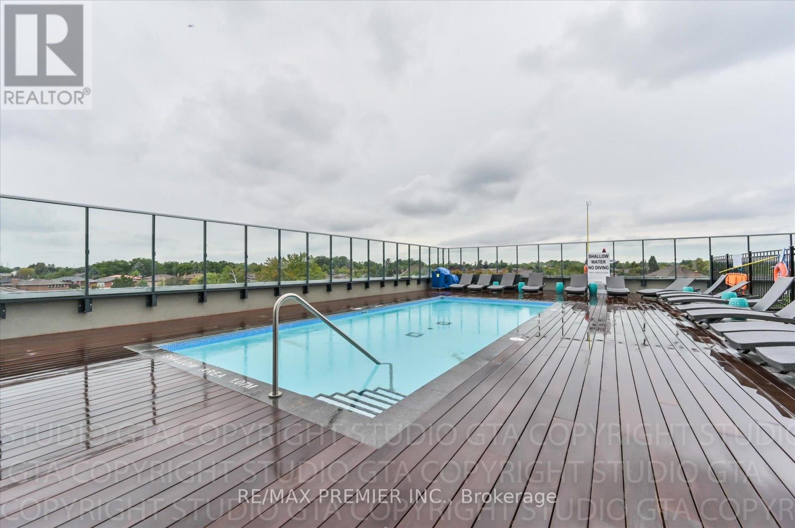 A pool surrounded by a wooden deck with chairs on it.