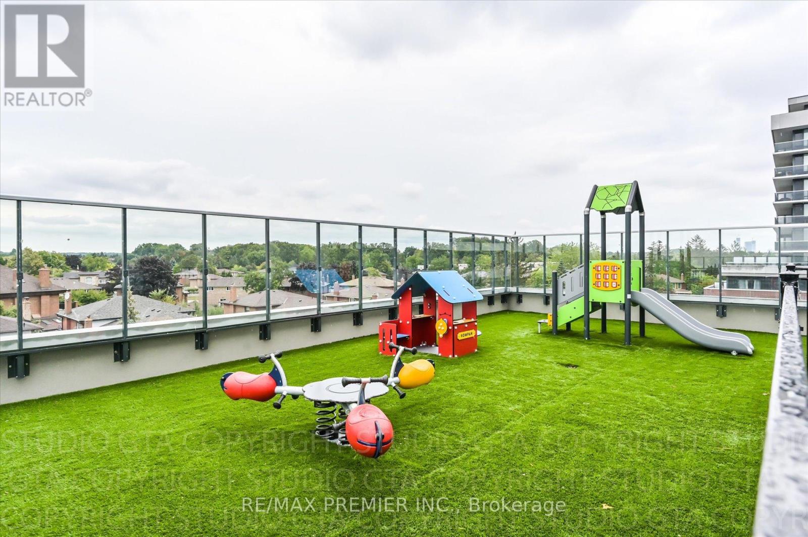 A playground with a slide, swings, and a ball is on a rooftop.