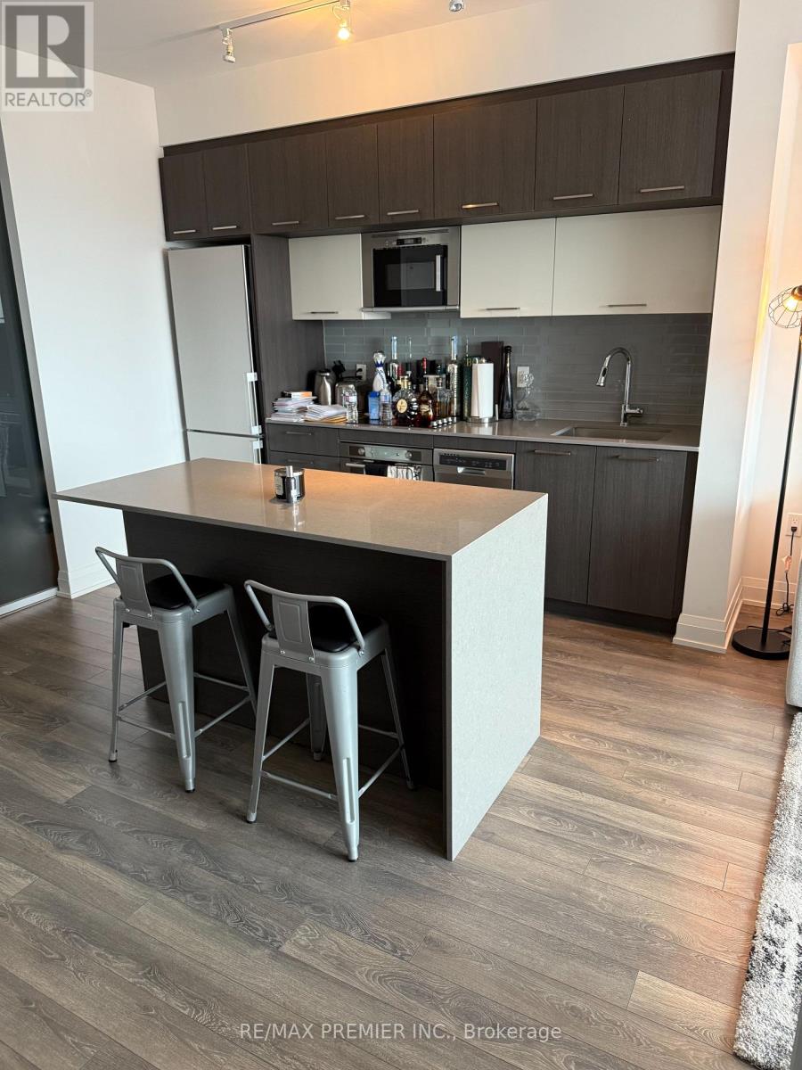 A kitchen with a white island and grey chairs.