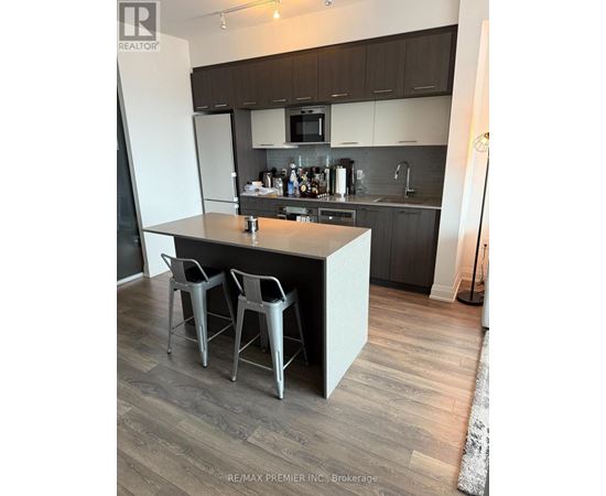 A kitchen with a white island and grey chairs.