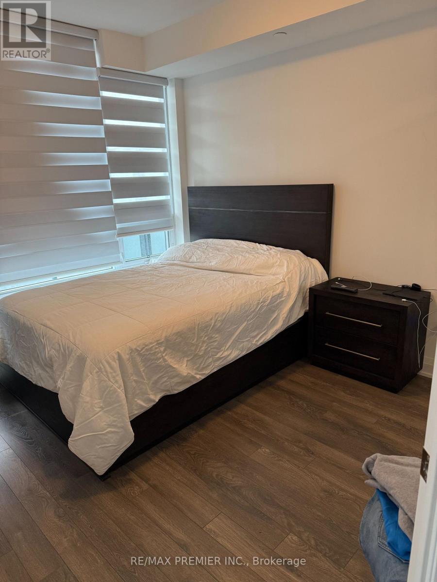 A bedroom with a bed, nightstand, and window with blinds.