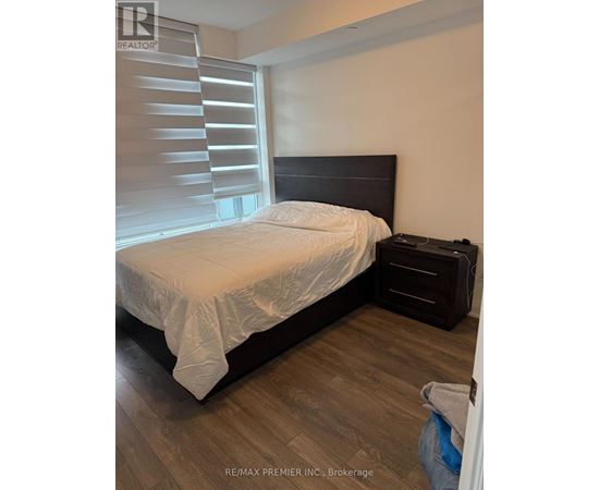 A bedroom with a bed, nightstand, and window with blinds.