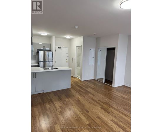 A large open room with wood flooring and white walls.