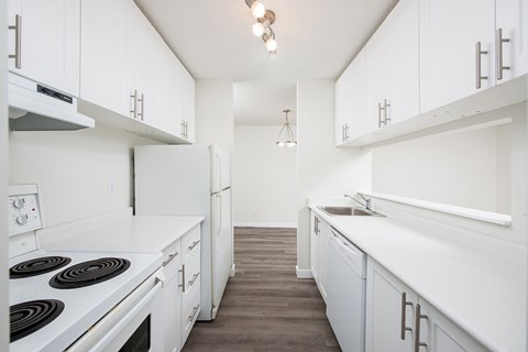 A kitchen with white cabinets and a stove top oven.