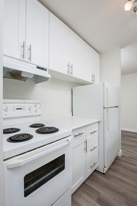 A white kitchen with a stove, oven, and refrigerator.