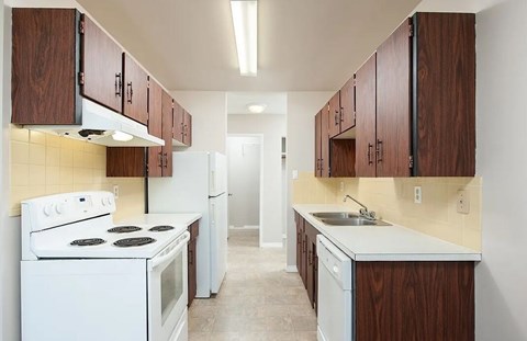 A kitchen with white appliances and wooden cabinets.