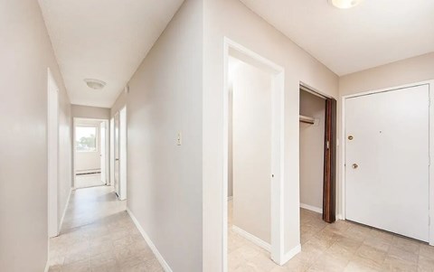 A long hallway with white walls and a tiled floor.