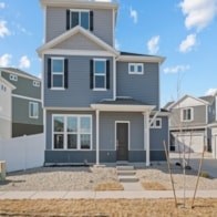 A grey house with a white fence in front.