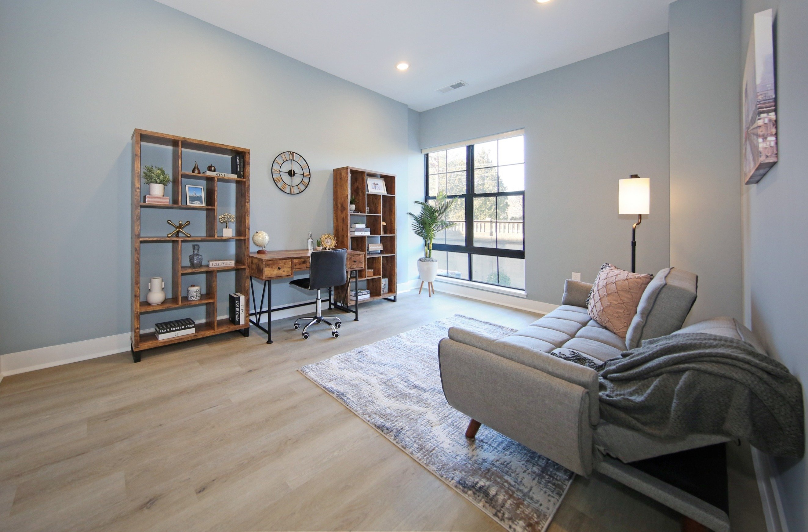 A living room with a grey couch and a wooden bookshelf.