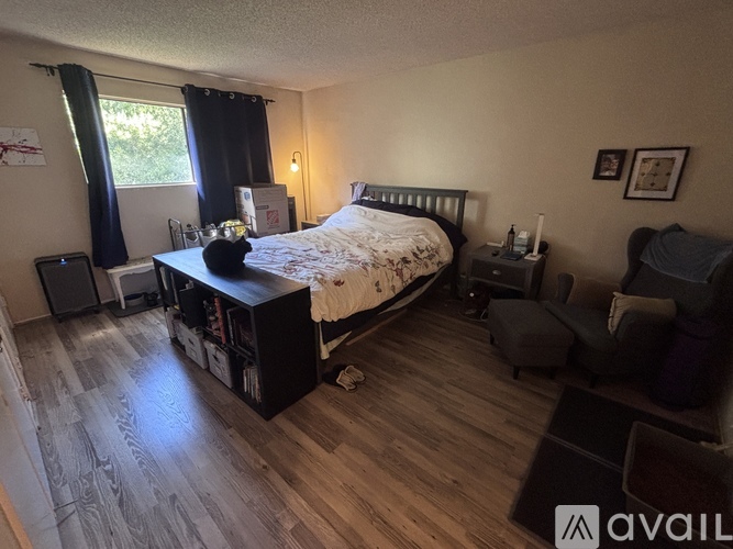 A bedroom with a bed, nightstand, and chair.