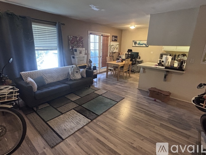 A living room with a grey couch and a kitchen area in the background.