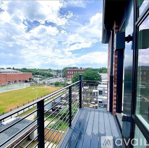 A balcony overlooks a green field and buildings.