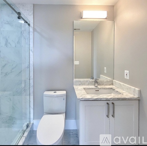 A white toilet sits next to a marble sink in a bathroom.