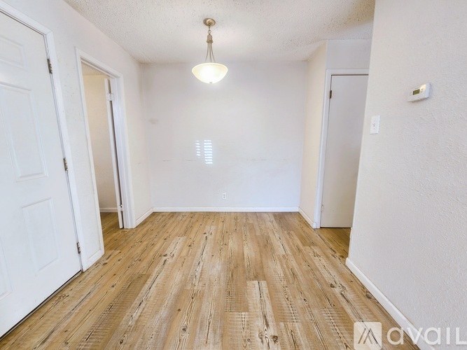 A room with wooden flooring and white walls.