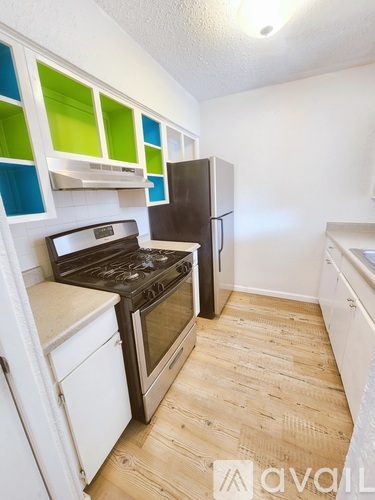 A kitchen with a black fridge, white cabinets and a white stove.