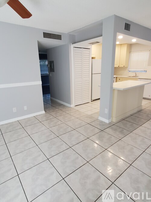 A spacious kitchen with white cabinets and a white tiled floor.