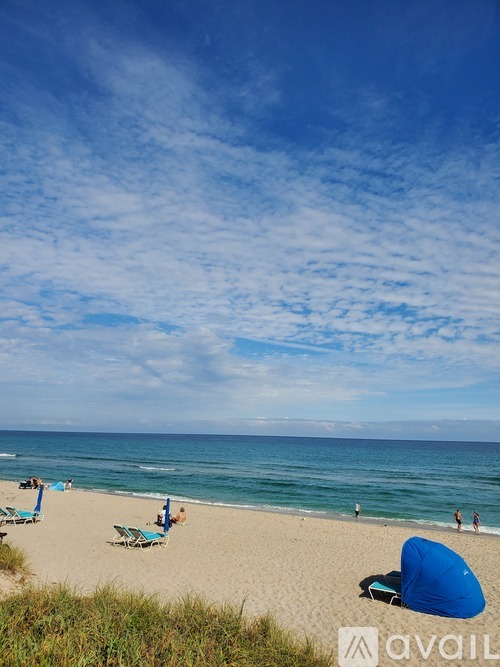 A beach scene with people relaxing on the sand and the ocean in the background.