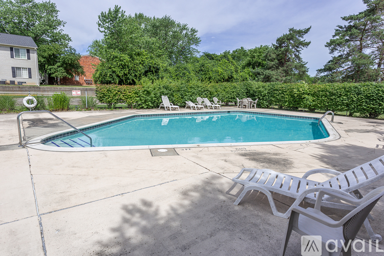 A pool surrounded by trees and chairs.