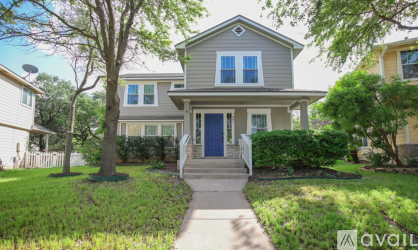 A house with a blue door and a tree in front.