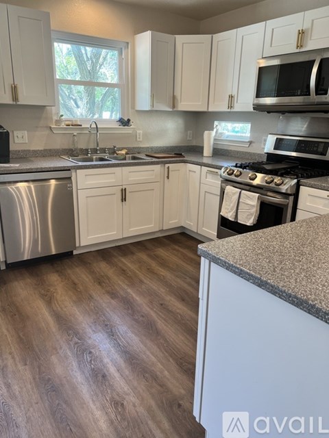 A kitchen with white cabinets and a granite counter.