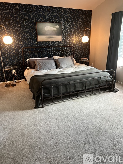 A bedroom with a large bed and a painting on the wall.