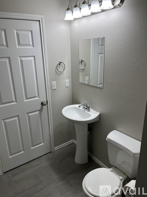 A white bathroom with a toilet, sink and mirror.