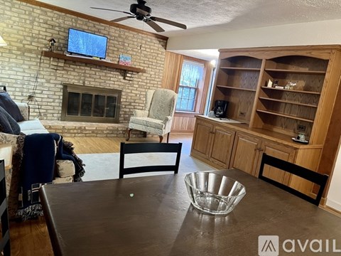 A living room with a brick fireplace and a television mounted above it.