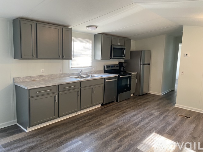 A kitchen with a refrigerator, microwave, and oven.