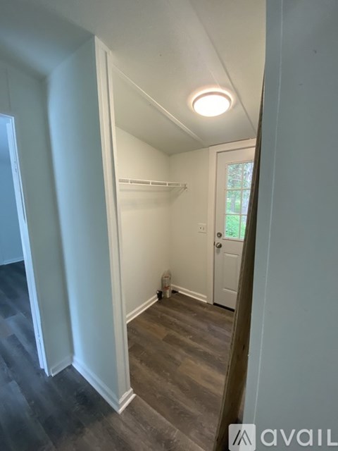 A hallway with a door on the right and a window on the left.