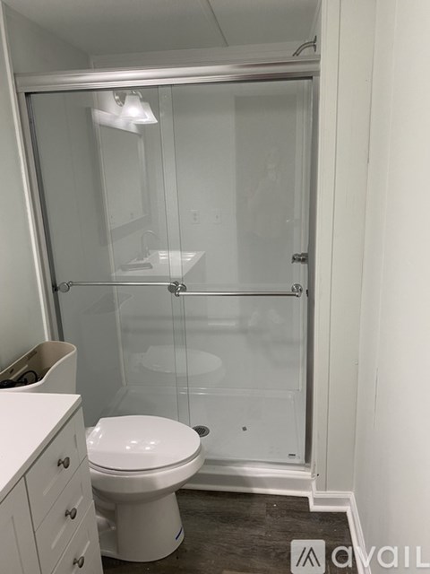 A white toilet sits in a bathroom next to a walk-in shower.