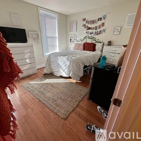 A bedroom with a bed, dresser, and a window with blinds.