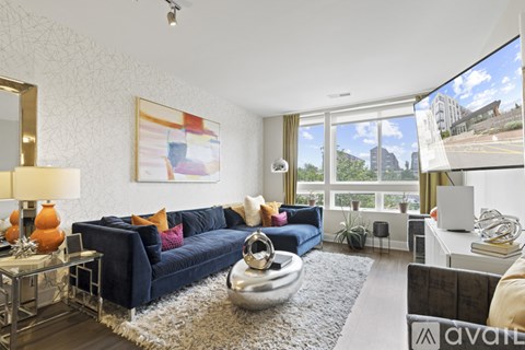 A living room with a blue couch and a large window.