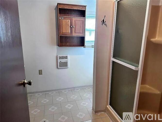 A room with a tiled floor and a wooden cabinet above a door.