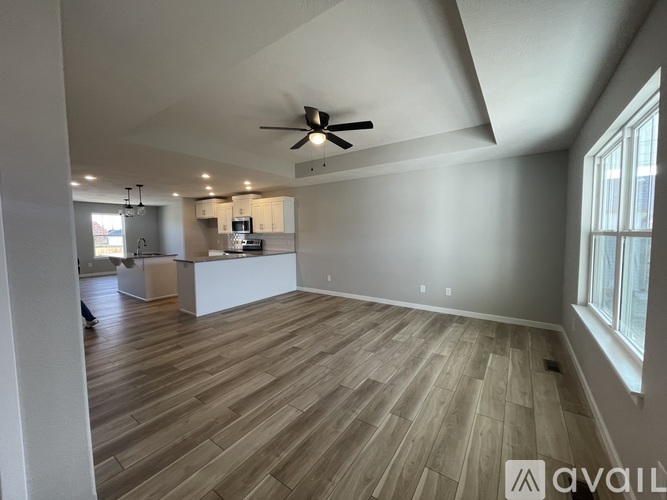 A spacious room with wooden flooring and a ceiling fan.