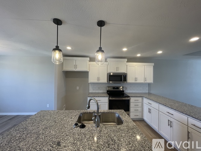 A kitchen with granite countertops and pendant lights.