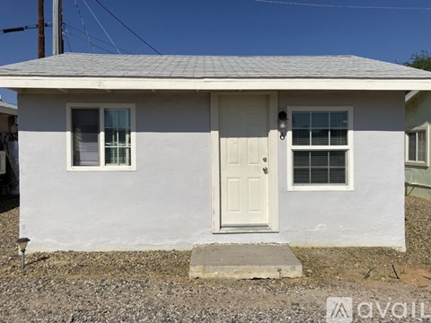 A small white house with a grey roof and a white door.