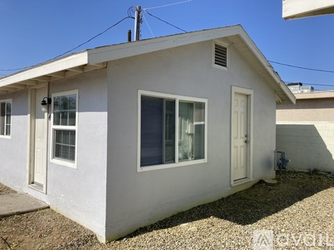 A small white house with a grey roof and a brown door.