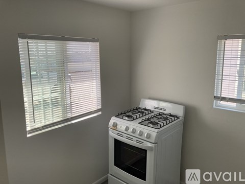 A white gas stove is in a kitchen with a window on the left.