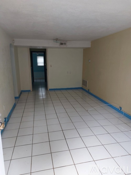 A room with a white tile floor and a door in the background.