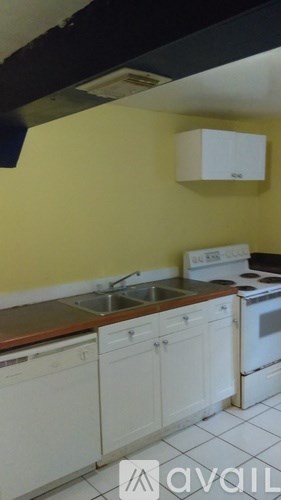 A kitchen with yellow walls and white cabinets.