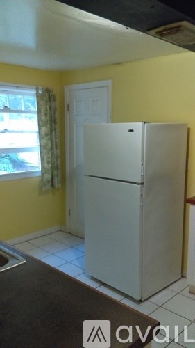 A white refrigerator in a kitchen with yellow walls.
