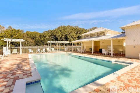 A large outdoor swimming pool surrounded by a tiled patio and lounge chairs.