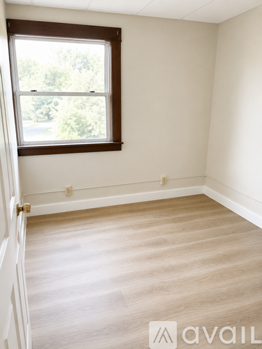 A room with a carpeted floor, a door, and a window with a black curtain.