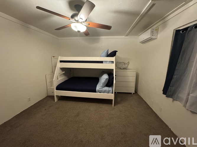 A small bedroom with a bunk bed and a ceiling fan.