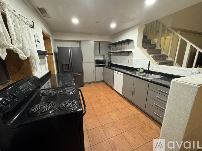 A kitchen with a black stove top oven and a tile floor.