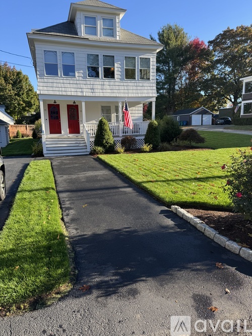 A white house with a red door and a flag on the front porch.