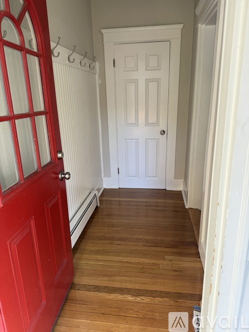 A hallway with a red door and a white door.