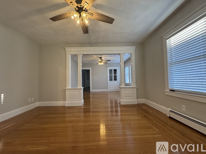 A spacious room with a ceiling fan and wooden flooring.