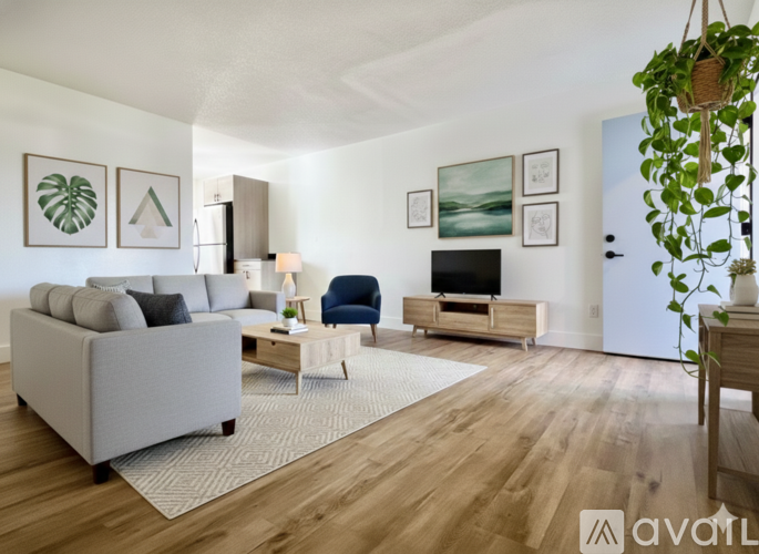 A living room with a grey couch, a blue armchair, a wooden coffee table, and a television.
